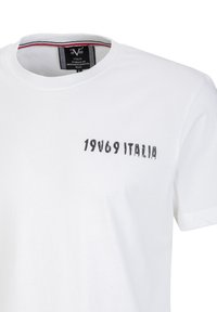 Witte katoenen t-shirt met een ronde hals en korte mouwen. De voorkant toont zwarte tekst "19V69 ITALIA" in een versleten stijl.