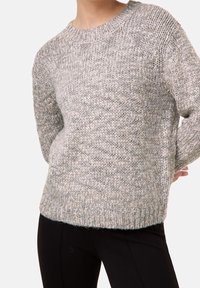Grå strikket sweater med rund halsudskæring, der har struktureret stof og en afslappet pasform. Lange ærmer med ribbede manchetter og kantdetaljer.
