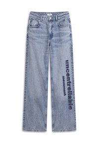 Jeans in denim azzurro chiaro con taglio a gamba larga. Presentano un lavaggio sbiadito e la scritta "movimento incontrollabile" stampata in blu scuro sulla gamba.