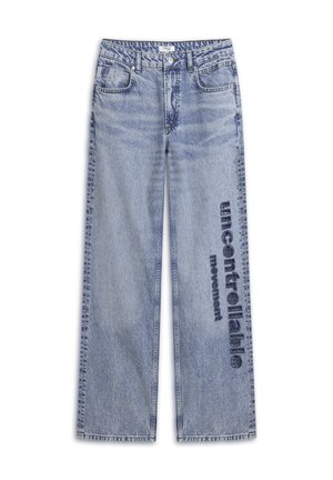 Jeans in denim azzurro chiaro con taglio a gamba larga. Presentano un lavaggio sbiadito e la scritta "movimento incontrollabile" stampata in blu scuro sulla gamba.
