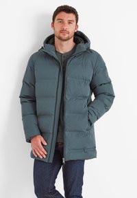 Dark teal puffer jacket with a hood, featuring quilted panels and a front zipper. Worn over a gray henley shirt and dark jeans.