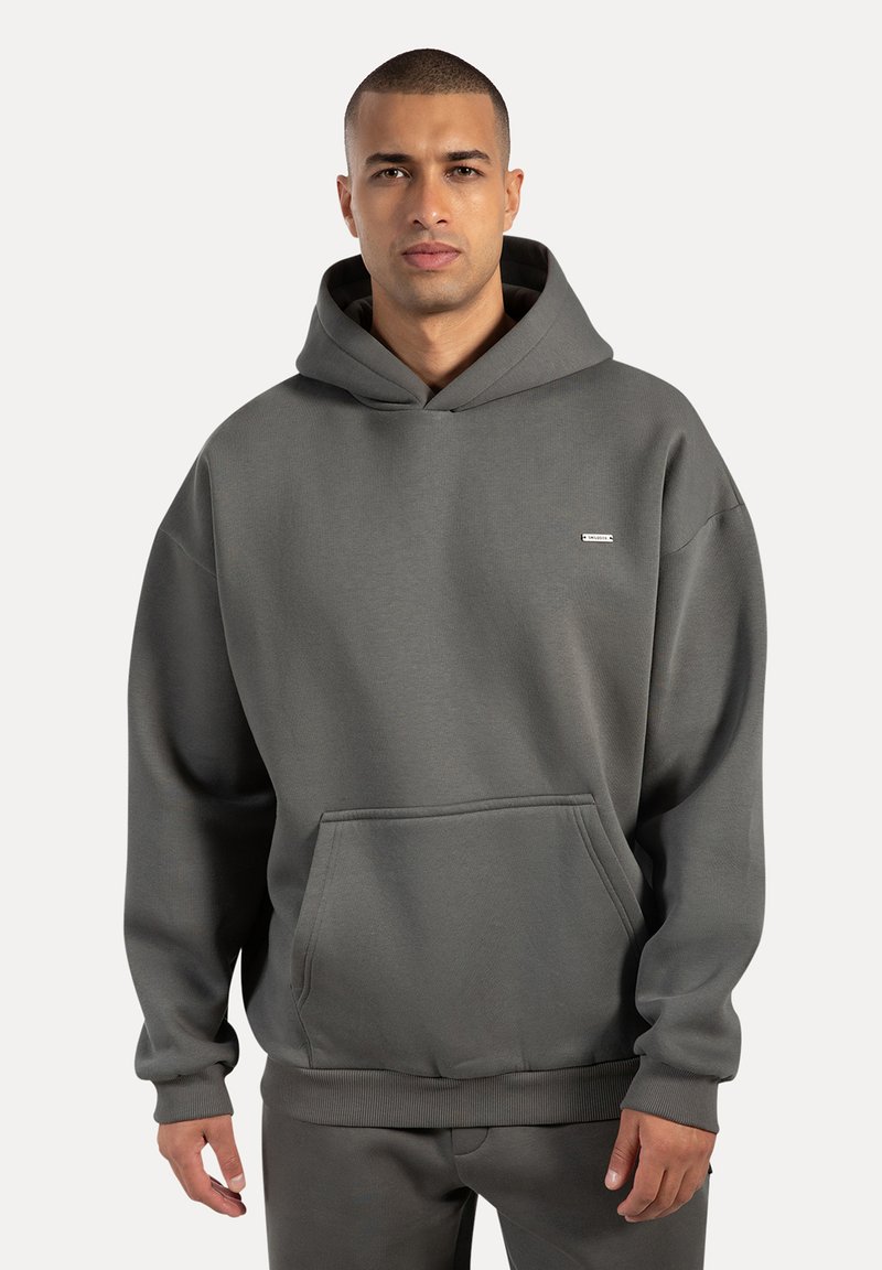 Felpa con cappuccio grigia realizzata in morbido tessuto, con tasca frontale e polsini a coste. Design minimalista con un piccolo logo sul petto.