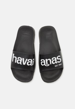 Sorte gummisandaler med en tekstureret sål. Har en bred rem med "havaianas EST. 1962" i fed hvid skrift.