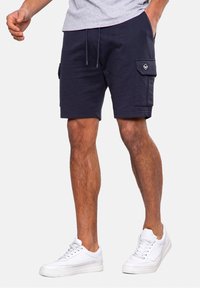 Navy cargo shorts made from cotton, featuring side pockets, a drawstring waistband, and contrasting logo detail on the pocket.
