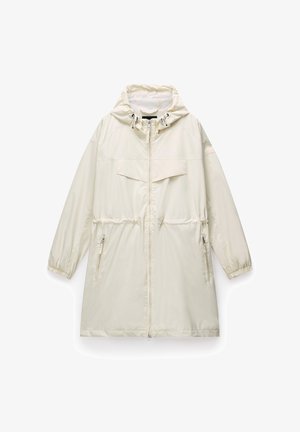 Parka impermeabile color beige chiaro con cappuccio, polsini elastici, due tasche laterali con cerniera e una tasca sul petto. Tessuto strutturato con vita arricciata.