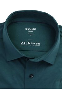 Ciemnozielona koszula z kołnierzykiem o nowoczesnym kroju, wykonana z elastycznego materiału dżersejowego. Posiada zapięcie na guziki oraz metkę z logo wewnątrz kołnierza.