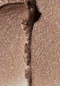 Metallisch bronzefarbener Lidschatten mit schimmerndem Finish, der eine weiche, cremige Textur und eine glatte Auftragsoberfläche bietet.