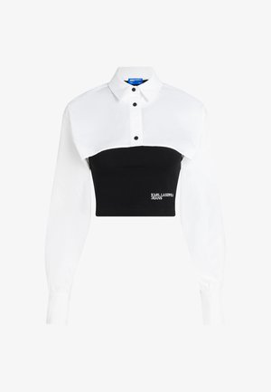 Camisa recortada que presenta una parte superior blanca con cuello y una parte inferior negra ajustada, con detalles de botones y el logo "KARL LAGERFELD JEANS" en la parte delantera.