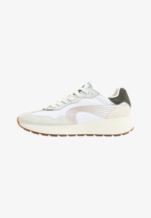 Zapatilla deportiva blanca con acentos de ante y malla. Presenta una superposición texturizada, detalles en beige y una suela de goma marrón claro.