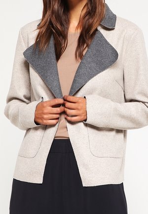 Hellgraue Wollmischungjacke mit einem dunkelgrauen Kragen, ausgestattet mit zwei vorderen Taschen und einer taillierten Passform. Der Stoff wirkt weich und strukturiert.
