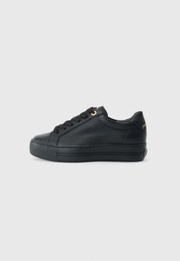 Basket basse noire en cuir texturé, dotée d'une semelle en caoutchouc, de lacets noirs et d'un accent doré sur le côté.