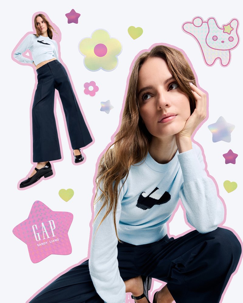 Valkoinen neulepaita, jossa on musta logo, yhdistettynä tummiin leveisiin housuihin. Malli poseeraa löysillä, hartiapituisilla hiuksilla. Värikkäitä graafisia elementtejä.