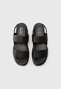 Svarte veganske sandaler med to brede, teksturerte stropper og en glatt såle, designet med åpen hæl for enkel påkledning.
