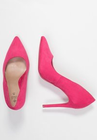 Chaussures à talons aiguilles en daim rose vif avec un bout pointu et un design découpé. Présente un talon brillant et lisse, ainsi qu'un intérieur doux.