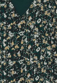 Tissu vert foncé avec imprimé léopard abstrait en beige, blanc et noir, agrémenté de fines rayures verticales métalliques dorées.