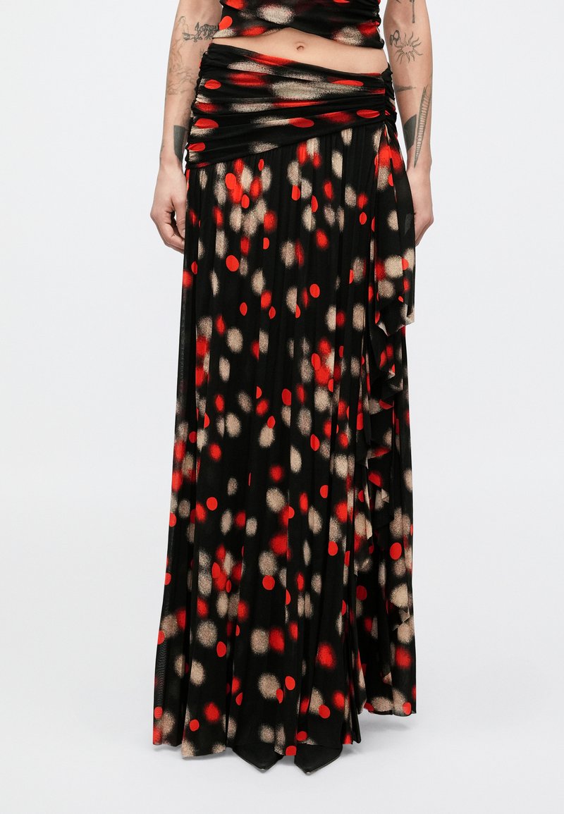 Maksi krilo iz lahkega blaga, s črno osnovo in rdečimi ter bež pikami, z dodatki volančkov ob robu.