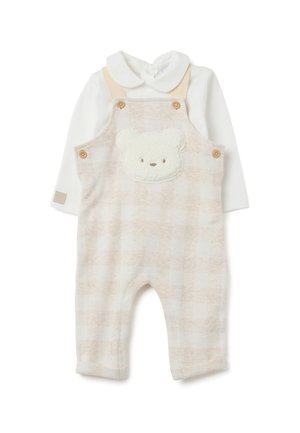 Pantalones de tirantes de bebé a cuadros beiges con un parche de oso esponjoso en la parte frontal, con botones de madera y una camiseta de manga larga blanca debajo.