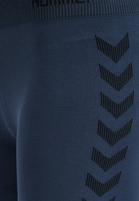 Leggings da atletica blu mare realizzati in un tessuto liscio e elasticizzato, con un motivo a chevron nero lungo il lato e una vita strutturata.