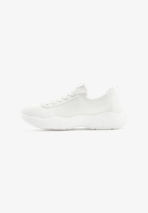 White athletic shoes with a knit upper, textured design, flexible sole, and a pull tab on the heel for easy wear.