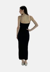 Robe noire à bretelles spaghetti présentant une silhouette ajustée, un design à la longueur des genoux et un tissu lisse et extensible de couleur unie.