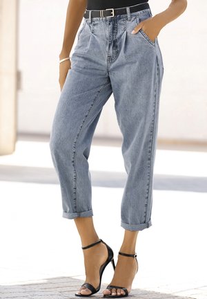 Light blue high-waisted denim jeans with a pleated front, rolled cuffs, and two side pockets, paired with black strappy high-heel sandals.