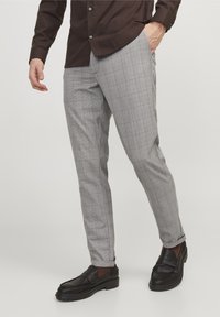 Grå rutig byxa med skräddarsydd passform, med subtila linjer i mörkare och ljusare nyanser. Matchas med svarta loafers.