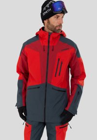 Röd och grå skidjacka i vattentätt tyg, med huva, flera fickor med dragkedja och kontrasterande paneldesign.