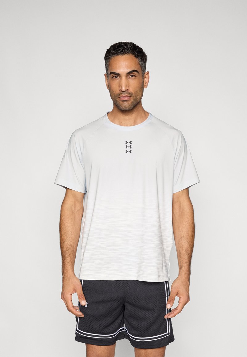 Αθλητική κοντομάνικη μπλούζα ανοιχτού γκρι με διακριτικό μοτίβο διαβάθμισης, λαιμόκοψη τύπου crew και κοντά μανίκια. Συνδυάζεται με μαύρο σορτς από δίχτυ με λευκές λεπτομέρειες.