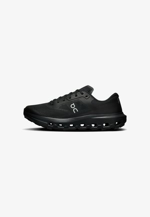 Chaussure de sport noire avec tige en mesh, fermeture à lacets et semelle épaisse perforée pour amorti et ventilation, vue de profil sur fond blanc.