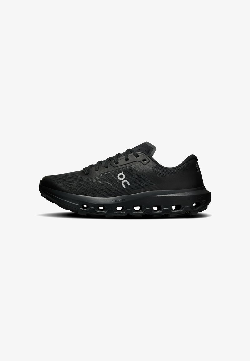 Chaussure de sport noire avec tige en mesh, fermeture à lacets et semelle épaisse perforée pour amorti et ventilation, vue de profil sur fond blanc.