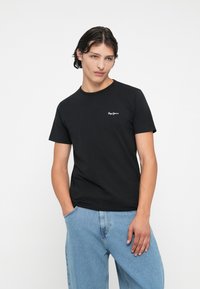 Tricou din bumbac negru cu guler rotund și mâneci scurte. Are un mic logo alb pe piept. Croială casual, textură netedă.