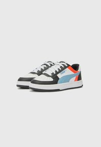 Zwarte, witte en lichtblauwe sneakers met een bovenwerk van gestructureerd leer, geperforeerde neus, witte veters en kleurrijke accenten aan de zijkanten.