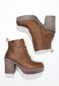 Brązowe botki z ekoskóry za kostkę, z wiązaniem z przodu, bocznym zamkiem błyskawicznym, masywnym obcasem i fakturowaną podeszwą. Posiadają pętlę do wkładania z tyłu.
