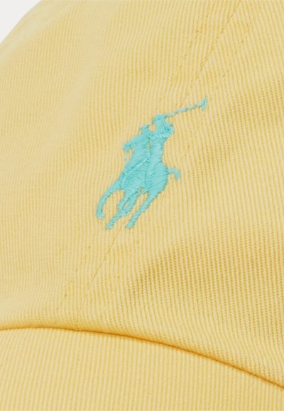 Gul kaps med en fremtredende turkise broderte hestelogo, med synlig ribbet tekstur og sømdetaljer.