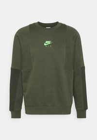 Olive green sweatshirt with a crew neckline, featuring a neon green Nike Air logo. Includes side panels and ribbed cuffs at the sleeves and hem.