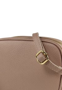 Peachkleurige leren tas met een korrelig oppervlak, voorzien van een goudkleurige gesp en ritssluiting. Heeft een textuur en een modern, minimalistisch ontwerp.