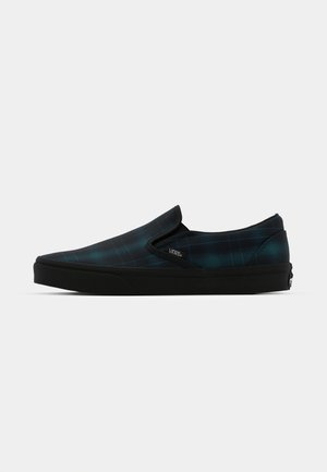 Slip-on Vans čevlji z dolgim plašnim vzorcem v temno zeleni in črni barvi, črn gumijast podplat ter brez vidnih vezalk ali kovinskih detajlov.