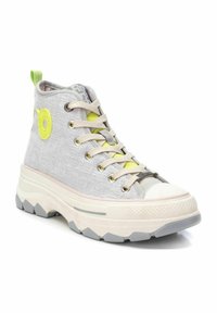 Zapatilla alta en tela gris claro con un acabado texturizado. Presenta acentos en verde lima, cordones beige y una suela de goma blanca gruesa.