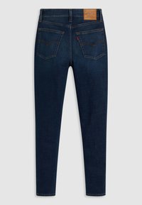 Tmavomodré džínsy slim-fit zobrazené zozadu, s dvoma zadnými vreckami, oranžovým prešívaním a hnedou nášivkou značky Levi's.