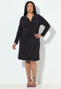 Schwarzes, glitzerndes Kleid mit langen Ärmeln, einem Kragen und einem verdrehten Vorderteil. Kombiniert mit burgunderfarbenen, geschnürten Absatzschuhen. Glatte Textur.