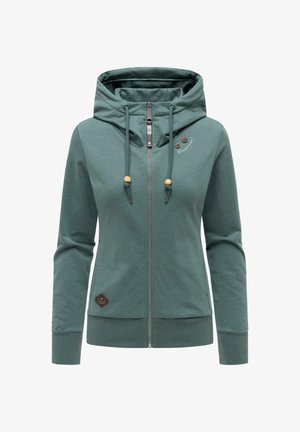 Grüner Kapuzenpullover mit Reißverschluss, hohem Kragen, Kordelzug mit Holzperlen, langen Ärmeln und kleinen Logo-Patches auf Brust und Saum.