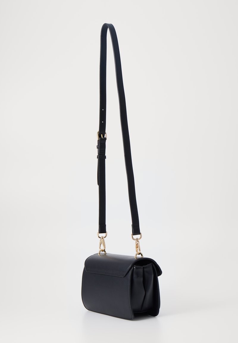 Sac à main en cuir noir avec une forme structurée, une bandoulière réglable et des accents en métal doré. Texture lisse avec un design à rabat.