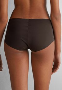 Bruine bikini onderkant van een gladde, rekbare stof. Kenmerkt zich door een eenvoudig, laag model met naadloze randen en een minimalistische snit.
