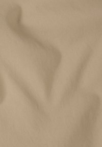 Μπεζ ύφασμα με λεπτή διαγώνια ραβδωτή υφή και διακριτικές πτυχώσεις που σχηματίζουν απαλές κυματιστές γραμμές.