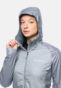 Hellgraue Jacke mit Kapuze, ausgestattet mit weichem Innenfutter, Reißverschluss und Logo auf der Brust. Schlanker Schnitt mit glattem, glänzendem Stoff.