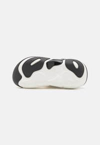 Shoe sole features a black and white design with textured patterns. It includes a semi-transparent section and curved edges for grip.