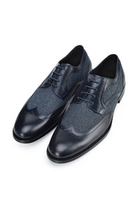 Zapatos de vestir azul marino con puntera y costados de cuero, con una parte superior de tela texturizada y detalles de costura intrincados.