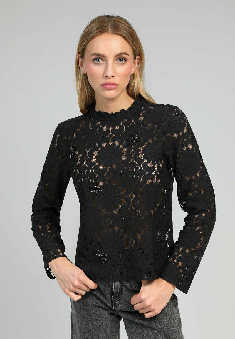 Blouse en dentelle noire à manches longues et col à volants. Motif floral avec des accents en perles pour plus de détails. Texture transparente.