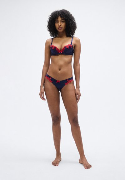 Granatowy komplet biustonosza i bikini z koronkową lamówką oraz czerwonymi akcentami; posiada wsparcie na fiszbinach, regulowane ramiączka oraz kokardki na majtkach.