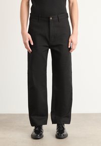 Black wide-leg trousers made of sturdy fabric, featuring a front button closure, side pockets, and a smooth, flat waistband.